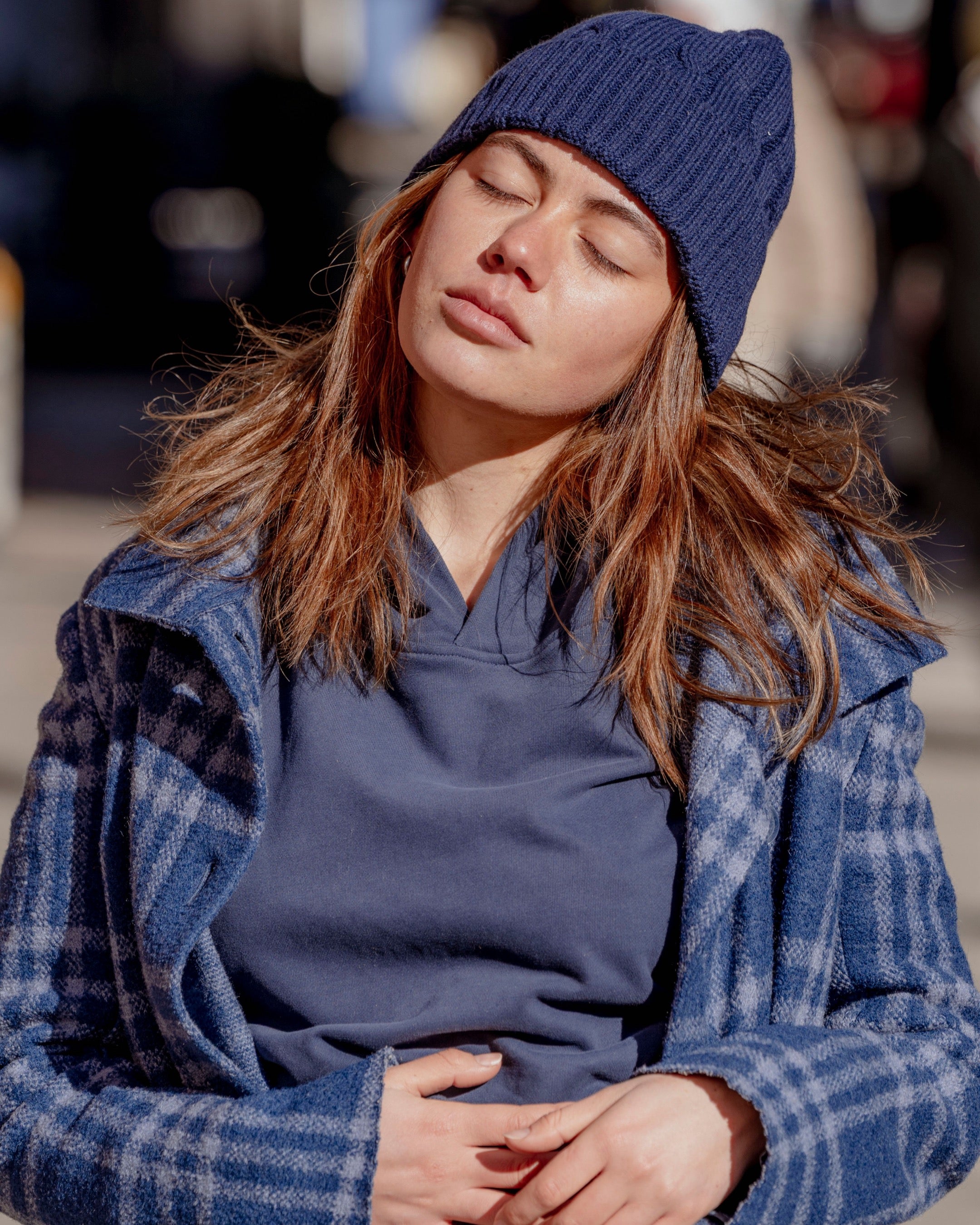 Person wearing a blue beanie and coat with a blurred background