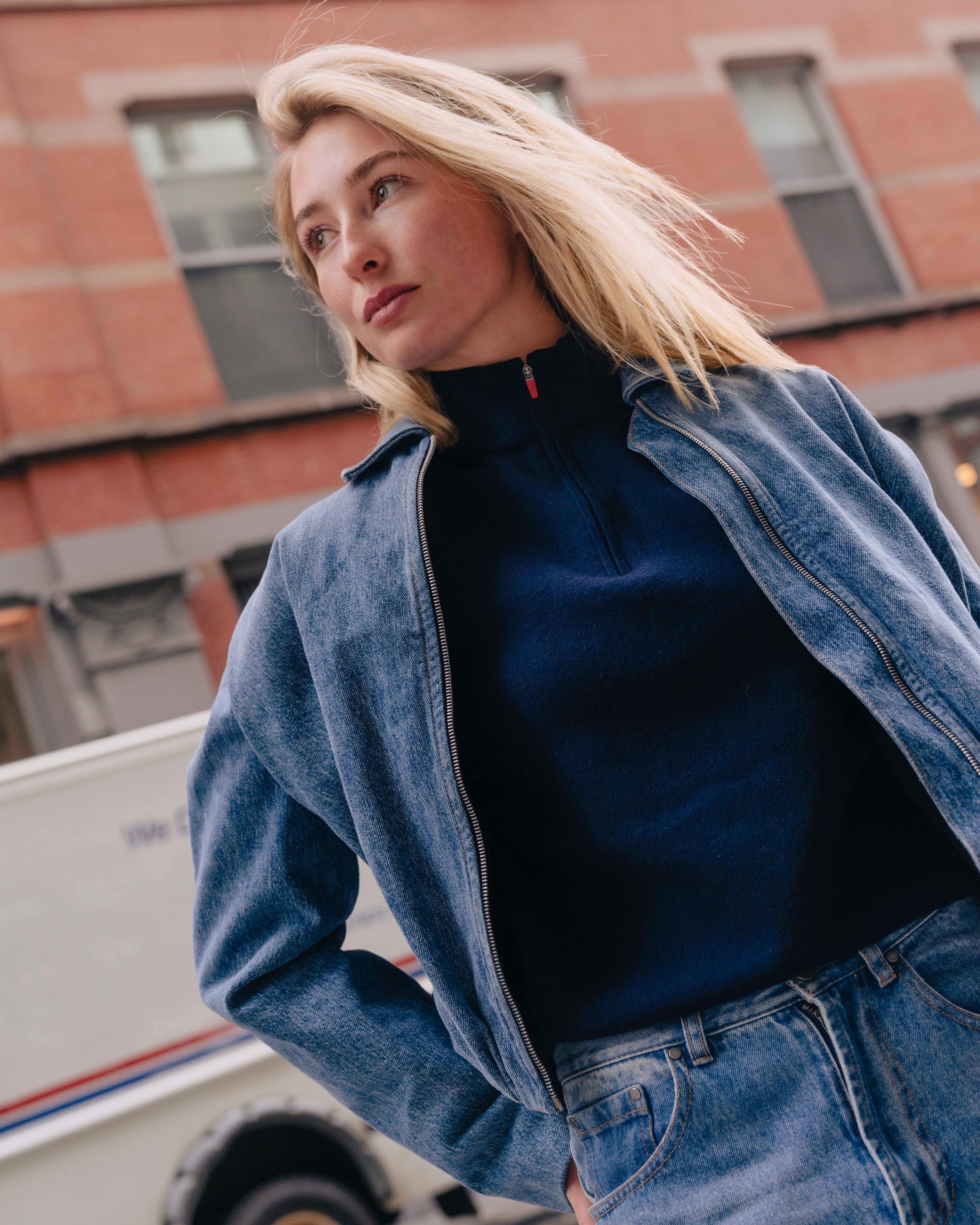 Woman wearing a blue denim jacket and black turtleneck in an urban setting