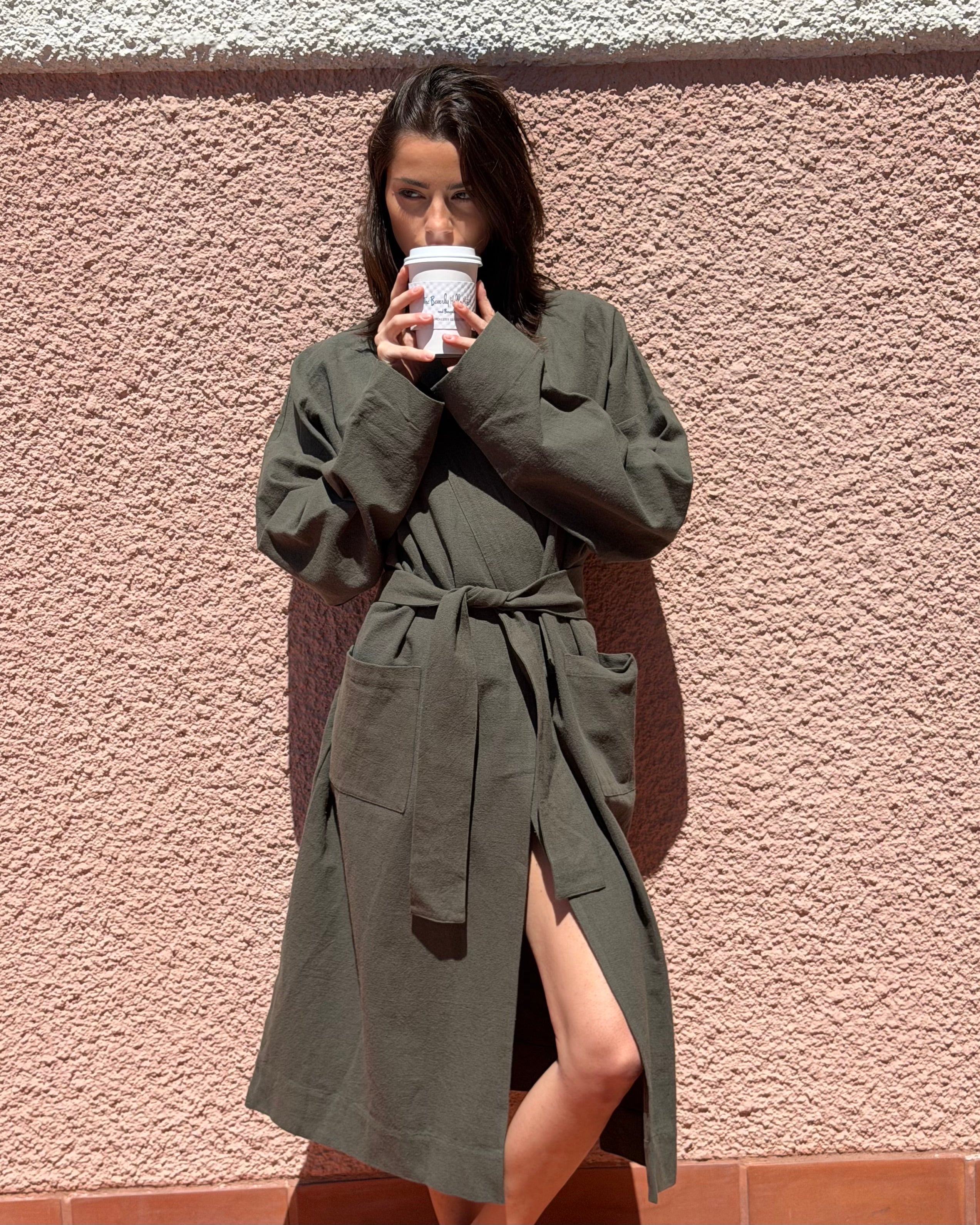 Woman wearing a green robe against a textured pink wall