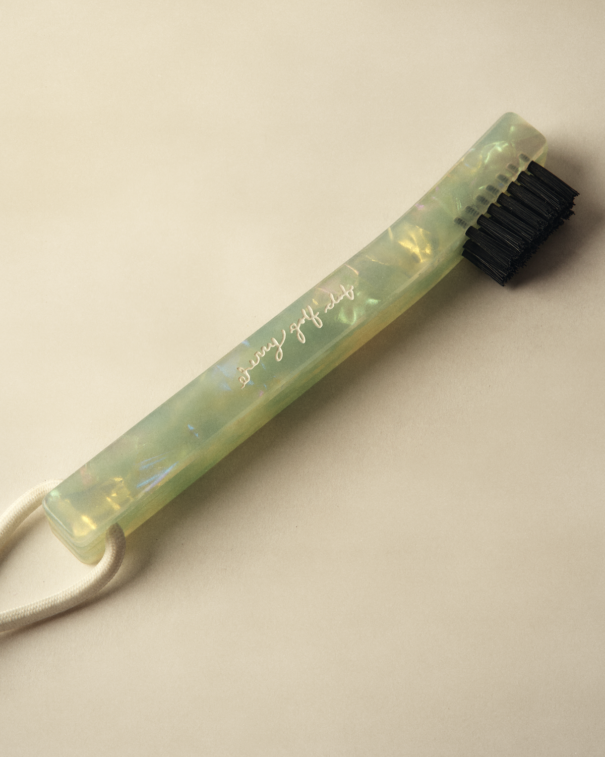 A translucent light green acrylic toothbrush holder with black bristles and a white cord, featuring the text 'stay healthy' in gold script, set against a warm beige background.