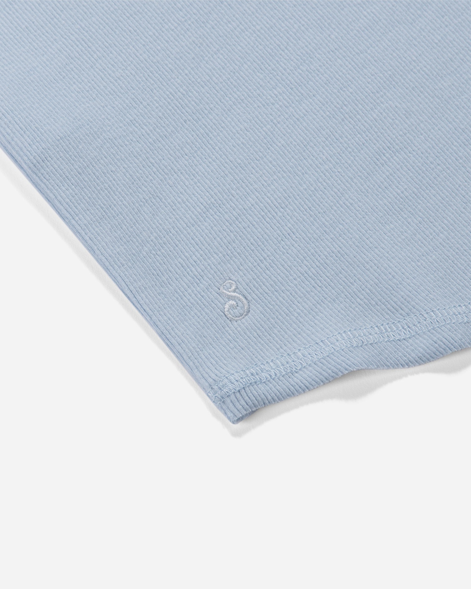 Close-up of a light blue fabric with a brand logo on a white background