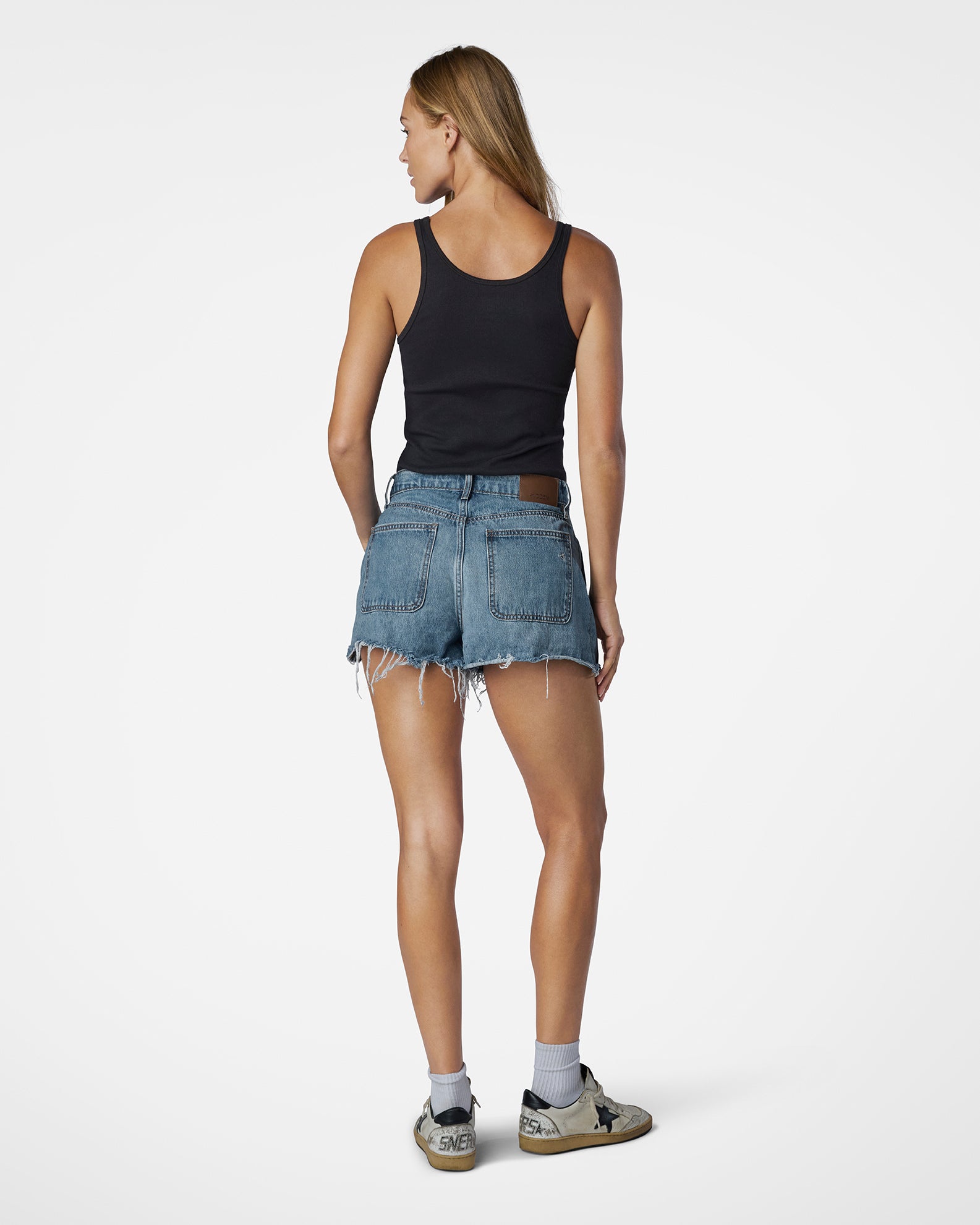 Person wearing a black tank top and denim shorts on a white background
