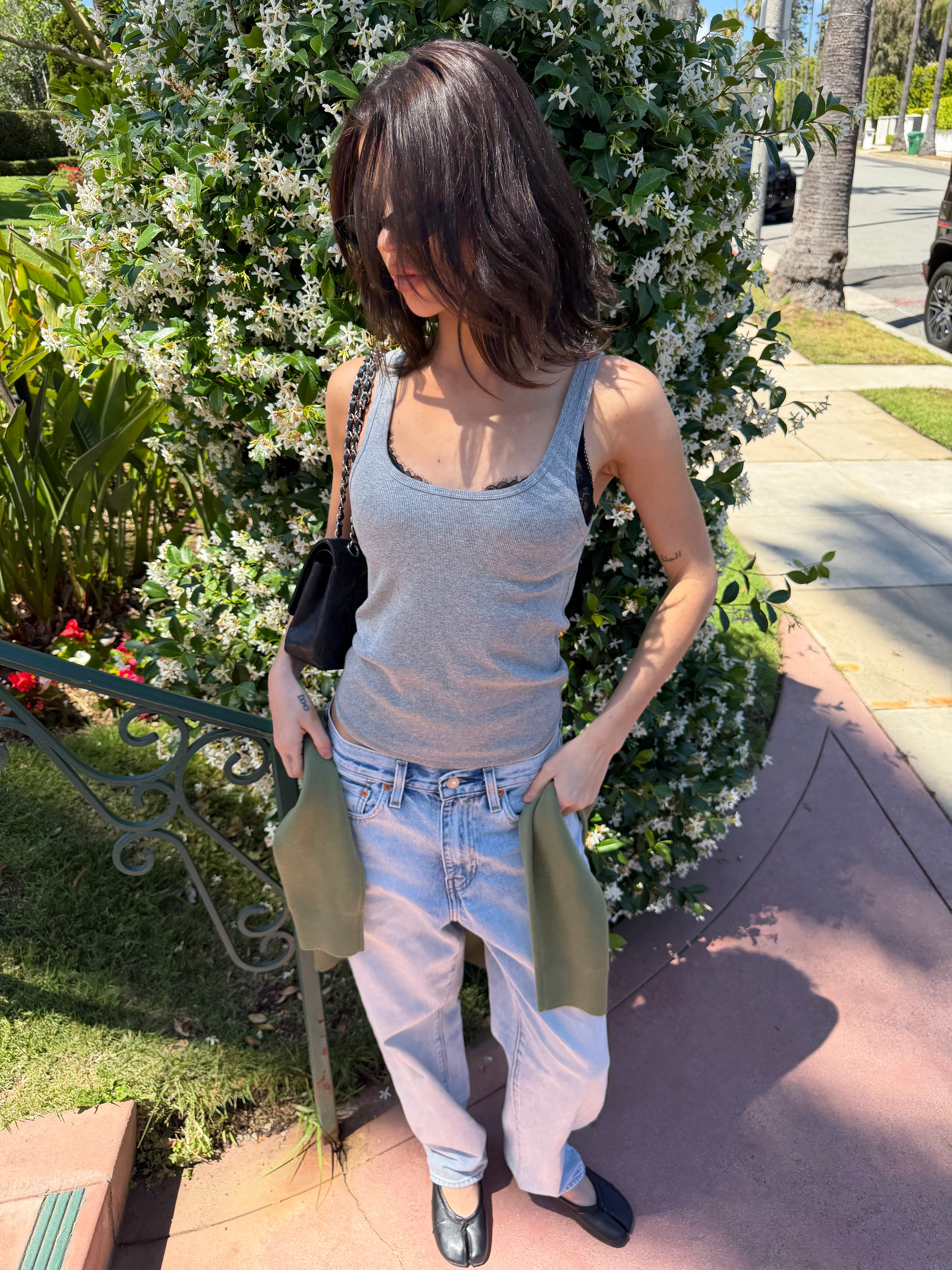 Woman standing outdoors with a floral bush in the background