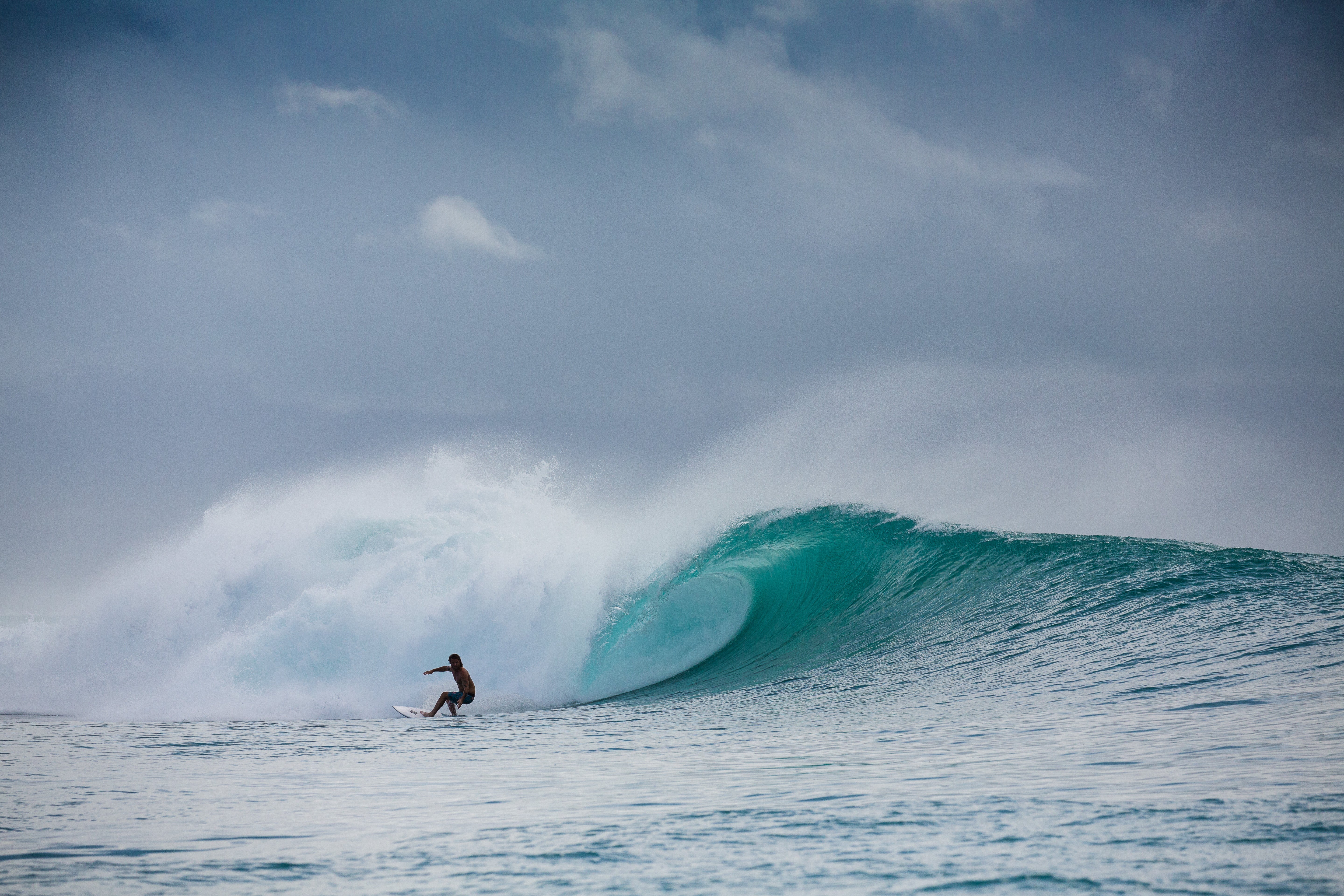 Surfer riding a large wave with a dramatic sky