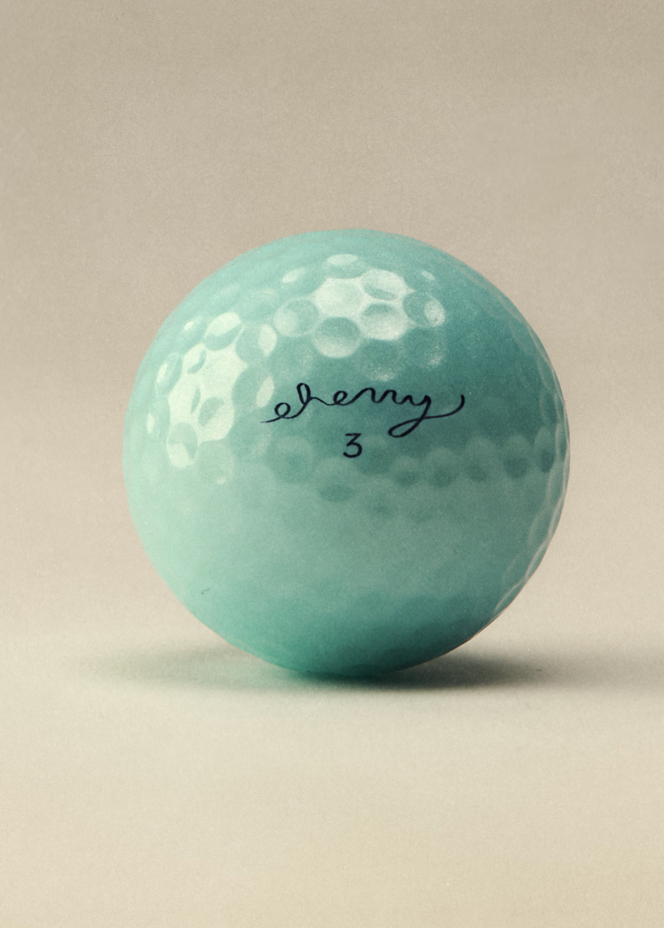 A single mint green golf ball with a black cursive signature reading 'Everly 3' on its side, photographed on a neutral beige background.