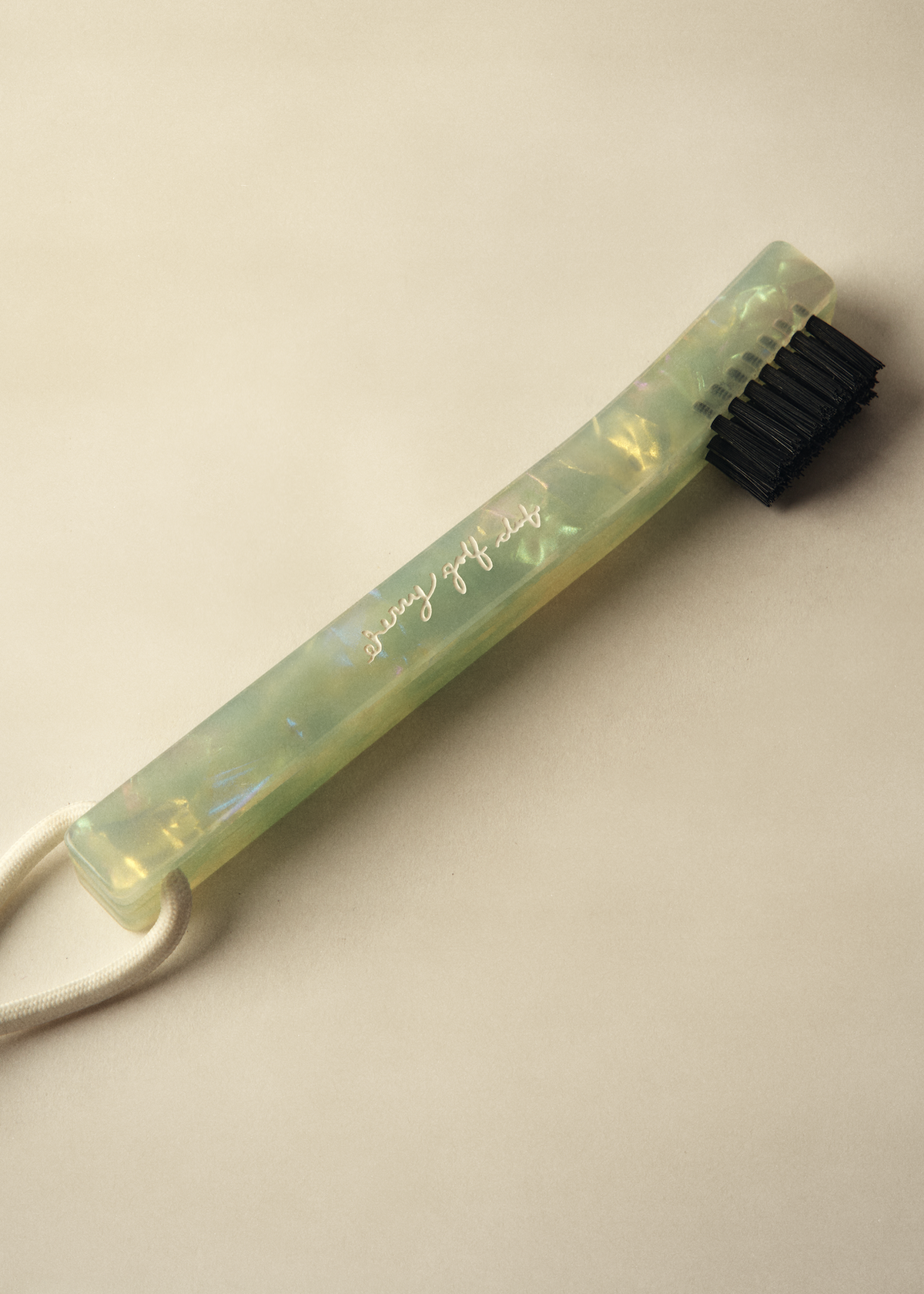 A translucent light green acrylic toothbrush holder with black bristles and a white cord, featuring the text 'stay healthy' in gold script, set against a warm beige background.