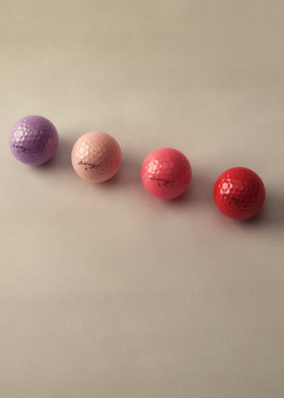 Four dimpled golf balls in purple, light pink, coral pink, and red, arranged diagonally on a warm beige background. Each ball features the 'shagway' brand name printed in black script.