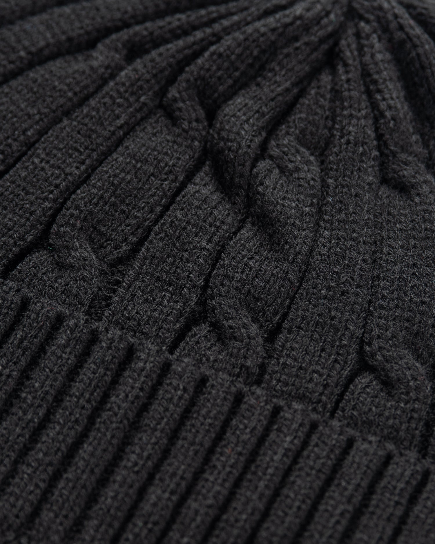 Close-up of a dark gray knitted cable-patterned beanie