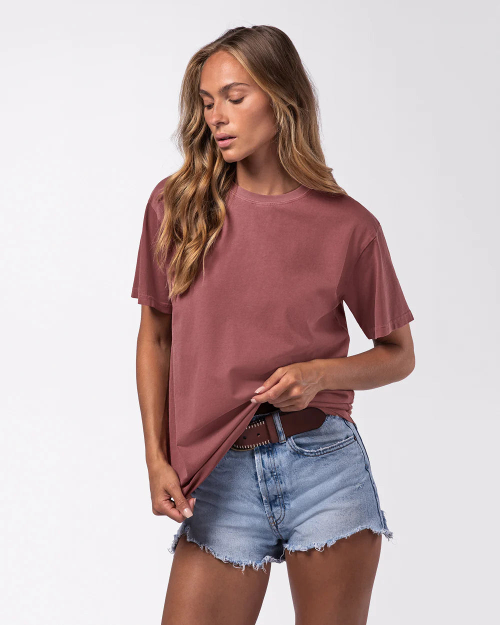 Woman wearing a maroon t-shirt and denim shorts on a white background