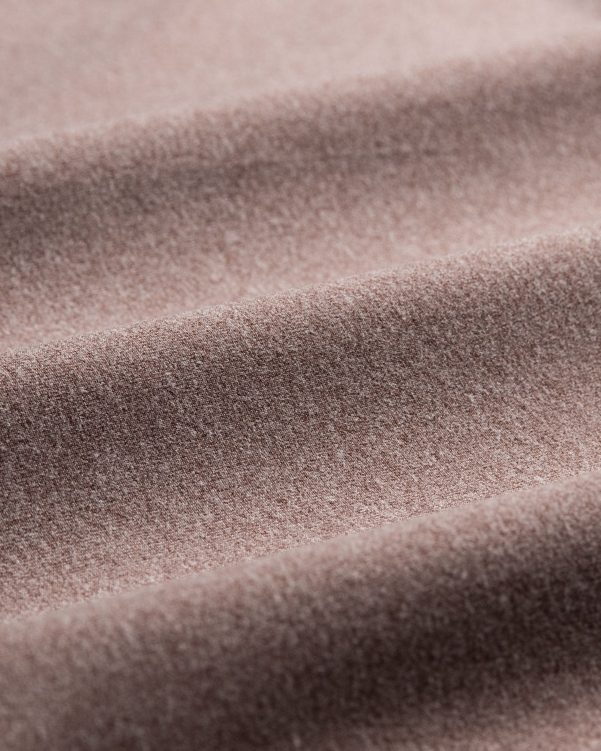 A close-up of draped dusty rose or mauve-colored fabric with a soft, textured surface.