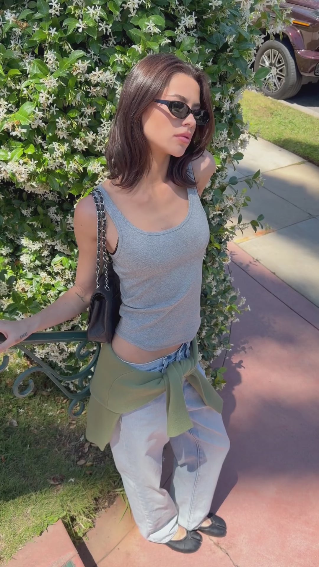 person wearing grey tank top posing with green background