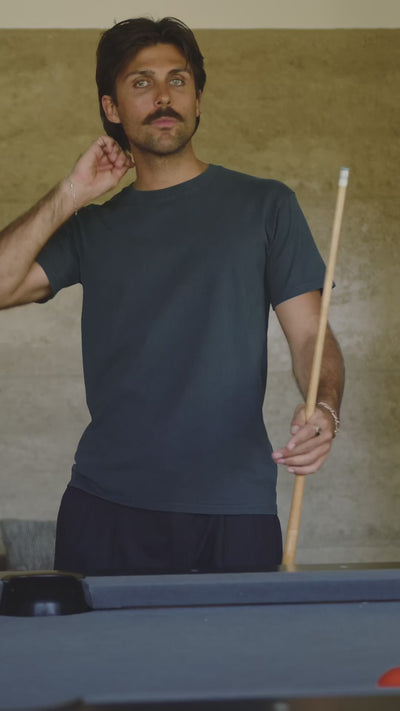 2 men wearing T-shirts in front of pool table and in garden setting