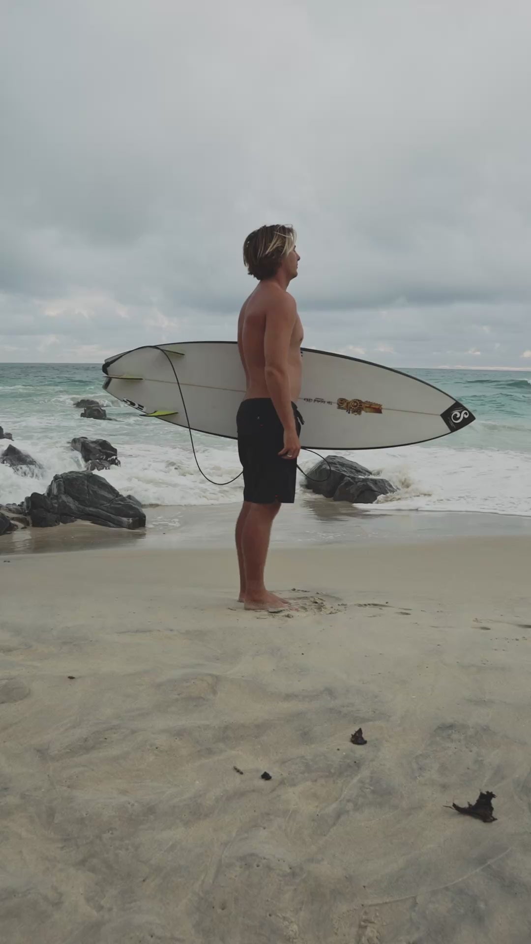 Person wearing black boardshorts on sandy beach