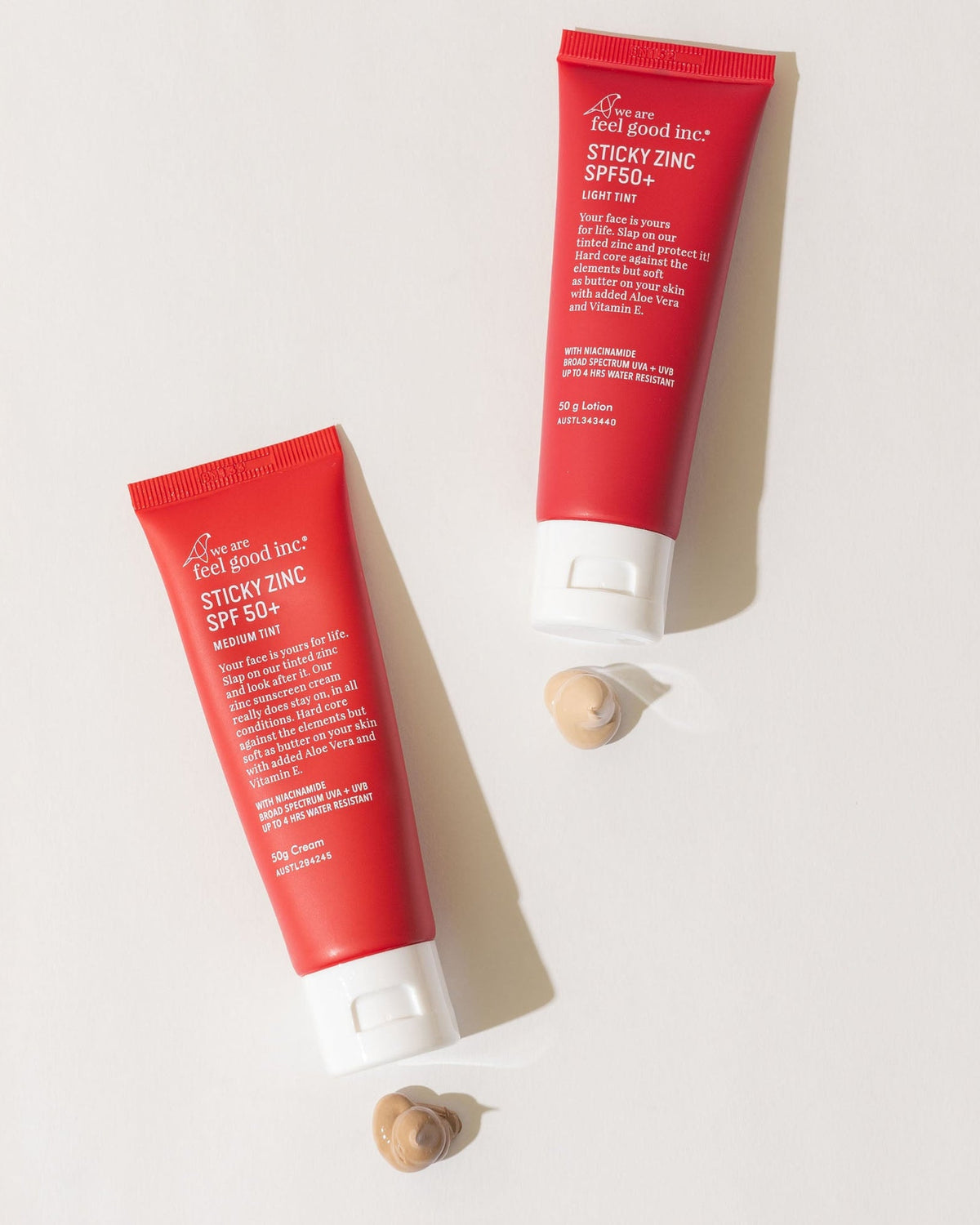 Two red tubes of 'Good Good' sticky zinc sunscreen on a light gray background